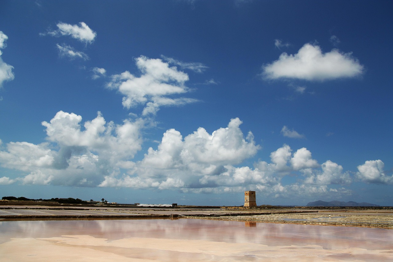 Saline di Trapani al tramonto, con mucchi di sale e palafitte in lontananza.