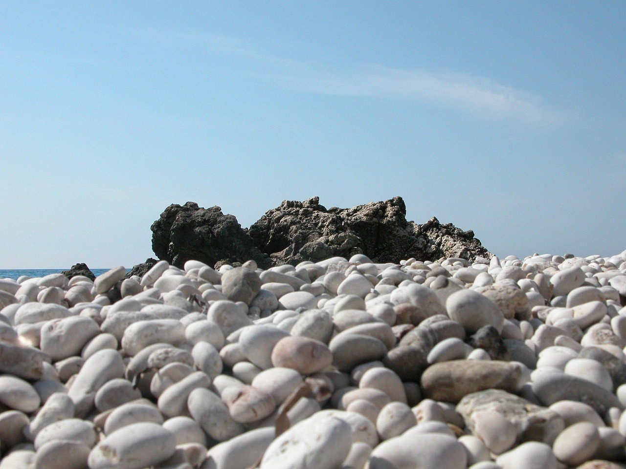 Spiaggia di ciottoli bianchi immersa nella natura, ideale per relax e tranquillità.