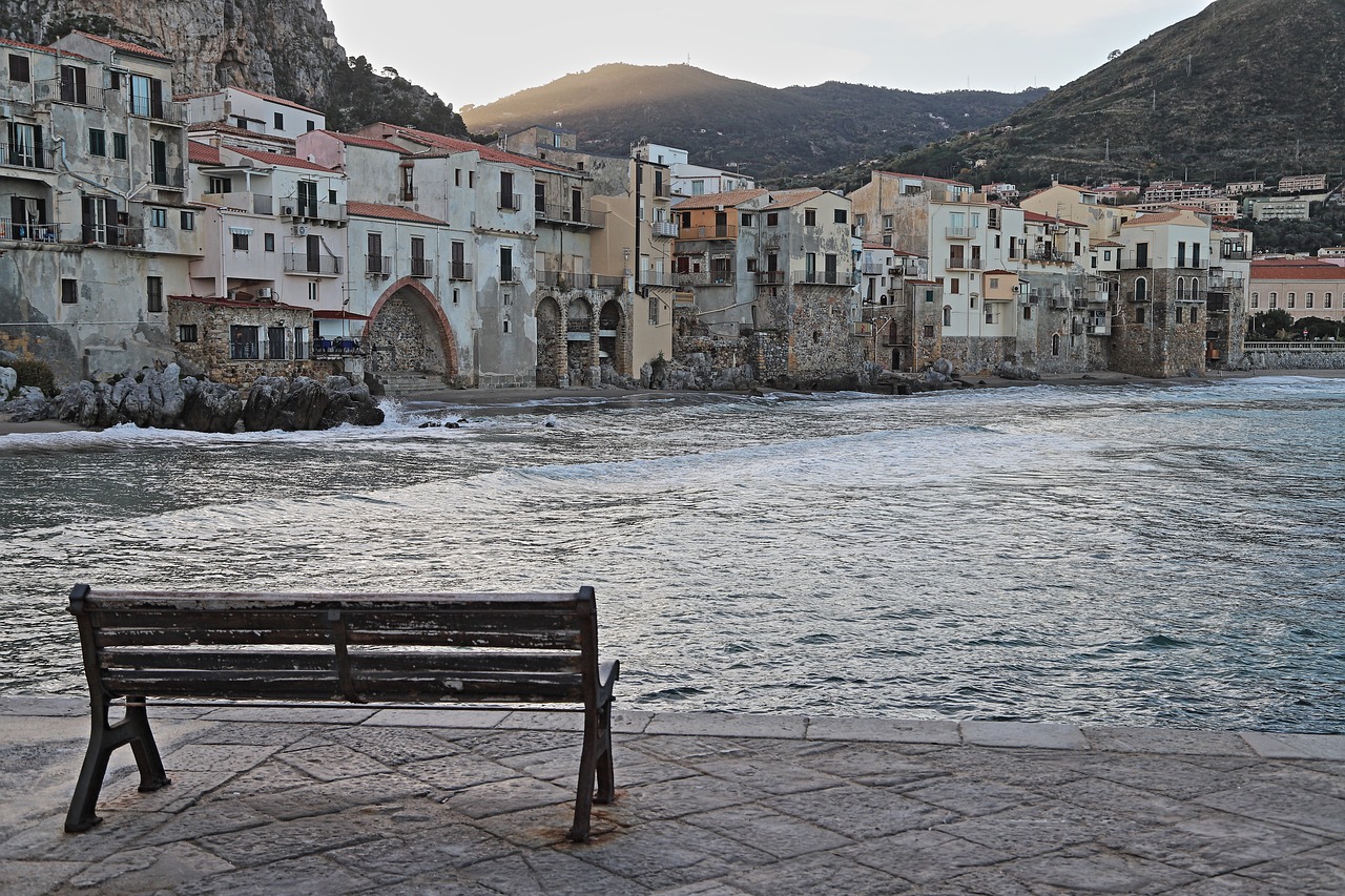 Vista serale di Cefalù con locali animati e passeggiate romantiche lungo il mare.