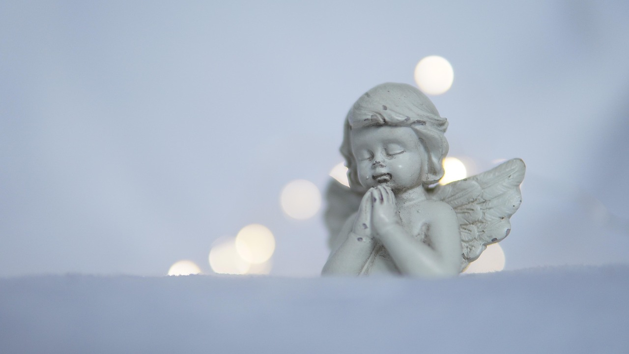 Una persona che prega con le mani giunte, circondata da candele e un'atmosfera serena.