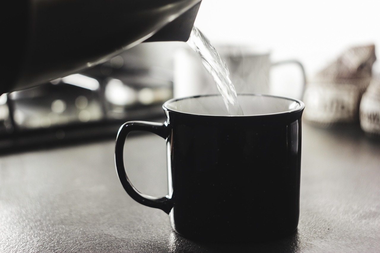Donna che beve acqua calda al mattino, con focus su benefici per colesterolo e glicemia.