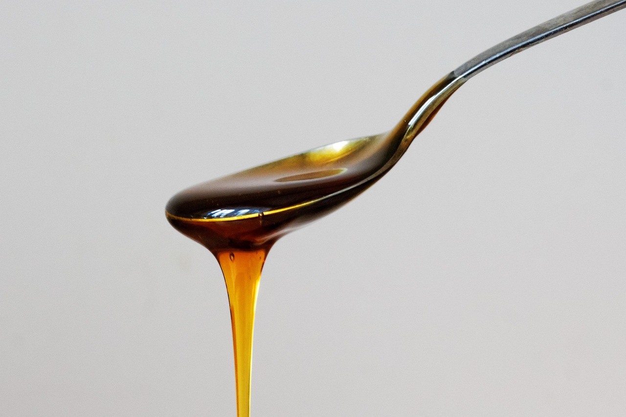 Cucchiaino di olio d'oliva su sfondo bianco, simbolo di salute e benessere per i centenari.