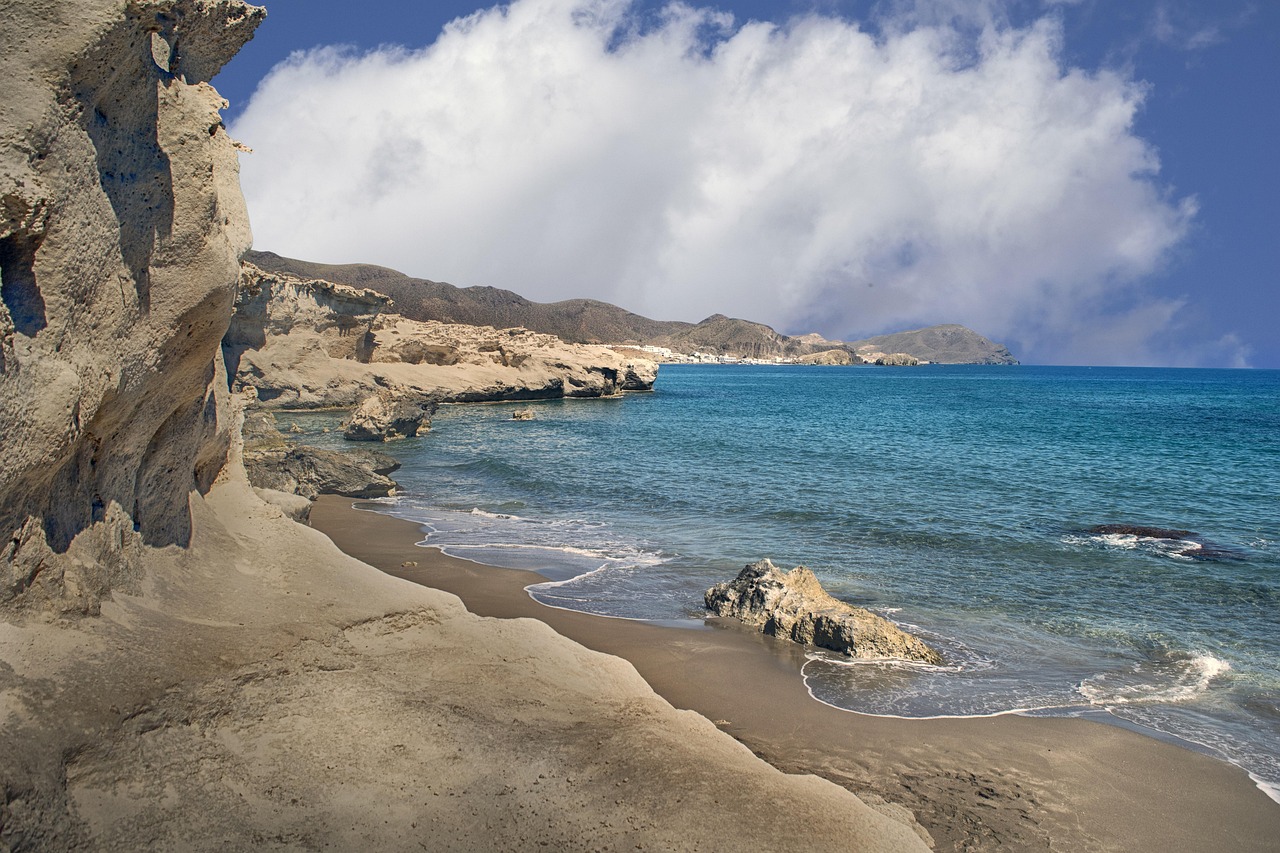 Spiaggia di sabbia nera vulcanica a Linosa, isola gemella di Lampedusa, con mare cristallino sullo sfondo.